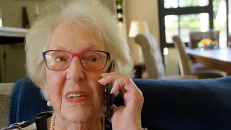 Senior-woman-talking-on-mobile-phone-in-living-room-4k