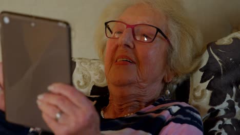Nahaufnahme-Einer-älteren-Frau,-Die-Ein-Digitales-Tablet-Auf-Dem-Bett-Im-Schlafzimmer-Nutzt,-4K