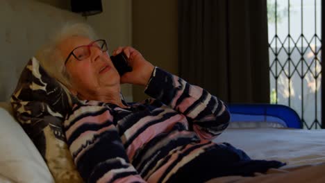 Senior-woman-talking-on-mobile-phone-in-bedroom-4k