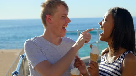 Happy-young-couple-having-fun-while-having-ice-cream-near-railings-4k