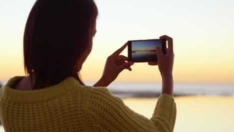 Beautiful-woman-capturing-sunset-on-mobile-phone-4k