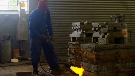 Worker-heating-metal-mold-with-blow-torch-in-foundry-workshop-4k