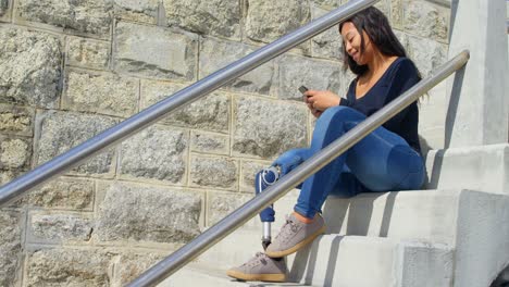 Seitenansicht-Einer-Behinderten-Frau,-Die-Auf-Der-Treppe-Eine-SMS-Mit-Dem-Mobiltelefon-Schreibt-4k