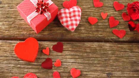 Gift-box-and-heart-shape-confettis-on-wooden-plank-4k