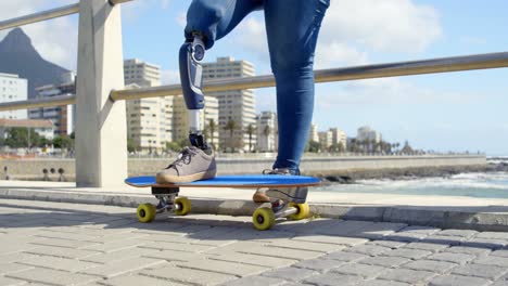 Low-section-of-disabled-woman-standing-with-skateboard-on-promenade-4k-