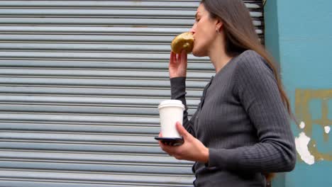 Woman-eating-donuts-while-walking-on-street-4k