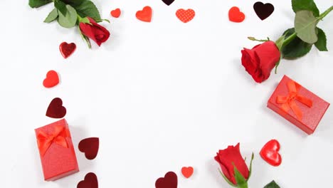 Red-roses,-gift-boxes-and-heart-shape-of-confetti-on-white-surface-in-circle-formation-4k