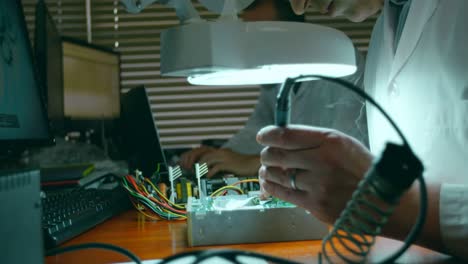 Male-robotic-engineer-assembling-circuit-board-at-desk-4k