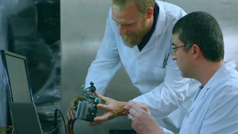 Male-robotic-engineers-discussing-over-electric-component-in-warehouse-4k