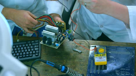 Robotic-engineers-examine-circuit-board-at-desk-4k