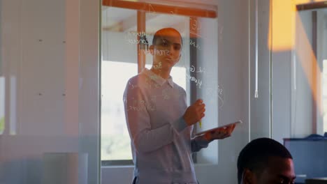 Front-view-of-young-caucasian-female-executive-looking-at-glass-wall-in-office-4k