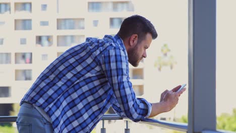 Side-view-of-young-caucasian-male-executive-using-mobile-phone-in-office-balcony-4k