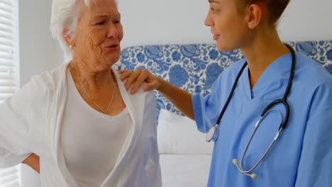 Caucasian-female-doctor-consoling-senior-woman-at-comfortable-home-4k