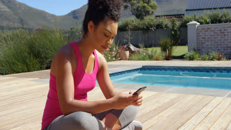 Side-view-of-young-mixed-race-woman-using-smartphone-in-backyard-of-home-4k