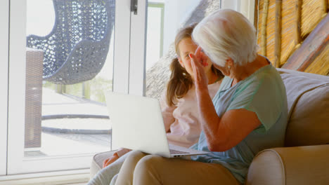 Side-view-of-Old-Caucasian-grandmother-and-granddaughter-using-laptop-in-a-comfortable-home-4k