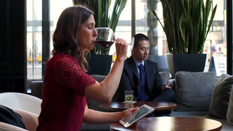 Businesswoman-using-digital-tablet-while-having-red-wine-in-hotel-4k