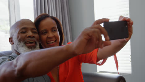 Front-view-of-mature-black-couple-clicking-selfie-with-mobile-phone-in-a-comfortable-home-4k