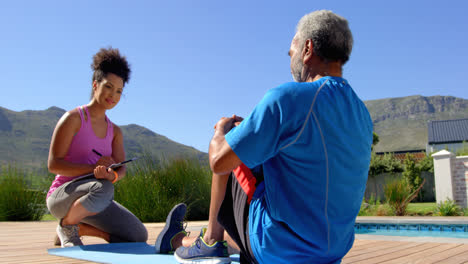Front-view-of-mixed-race-personal-trainer-exercising-with-determined-senior-black-man-in-backyard-4k
