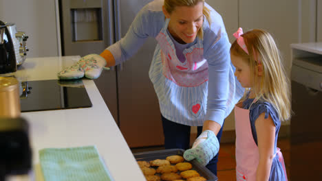 Front-view-of-young-Caucasian-mother-and-daughter-baking-cookies-in-kitchen-at-home-4k