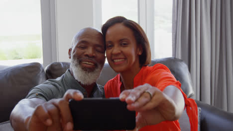 Vorderansicht-Eines-Reifen-Schwarzen-Paares,-Das-In-Einem-Komfortablen-Zuhause-4K-Auf-Ein-Selfie-Mit-Dem-Mobiltelefon-Klickt