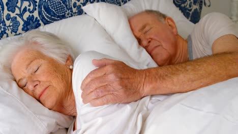 Caucasian-senior-couple-sleeping-on-bed-in-bedroom-at-comfortable-home-4k