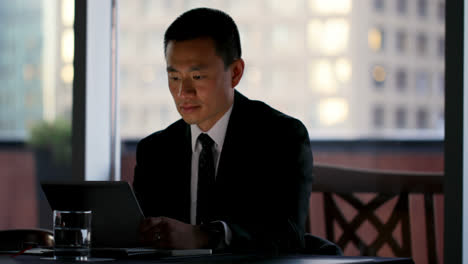 Front-view-of-young-Asian-Businessman-working-on-digital-tablet-in-the-modern-hotel-4k