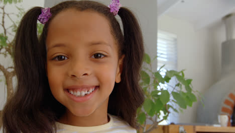 Front-view-of-cute-little-black-girl-looking-at-camera-in-a-comfortable-home-4k