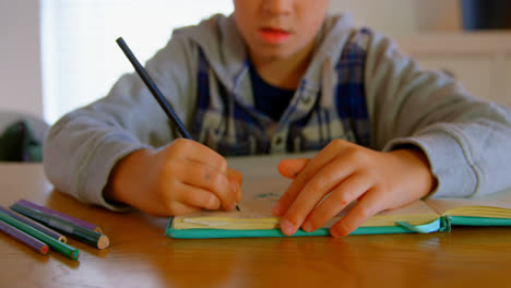 Front-view-of-Caucasian-boy-doing-his-homework-at-dining-table-in-a-comfortable-home-4k
