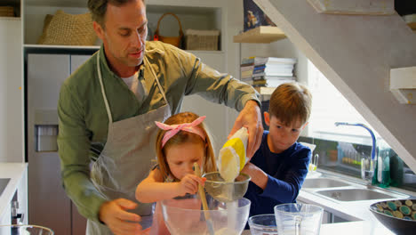 Front-view-of-young-Caucasian-father-and-children-preparing-food-in-kitchen-of-comfortable-home-4k