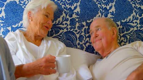 Front-view-of-Caucasian-senior-couple-interacting-with-each-other-on-bed-at-comfortable-home-4k