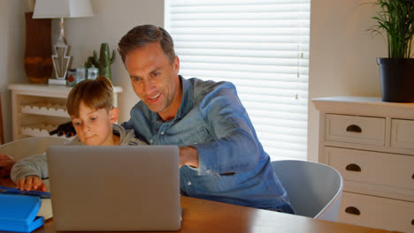 Front-view-of-young-Caucasian-father-helping-son-with-homework-at-table-in-a-comfortable-home-4k