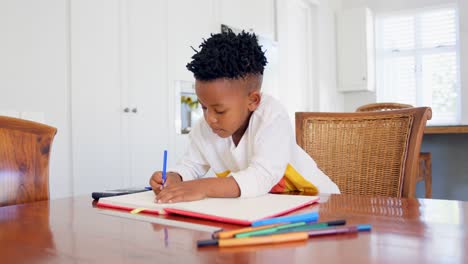 Front-view-of-attentive-black-boy-doing-his-homework-at-comfortable-home-4k