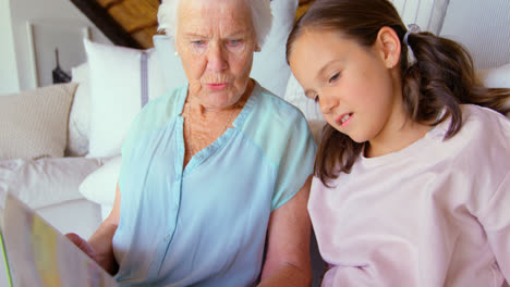 Front-view-of-Caucasian-Grandmother-and-granddaughter-reading-a-book-in-a-comfortable-home-4k