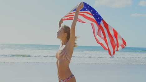Frau-Hält-Eine-Amerikanische-Flagge-Am-Strand-4k