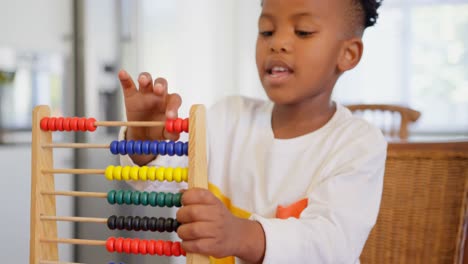 Front-view-of-black-boy-playing-with-abacus-at-comfortable-home-4k