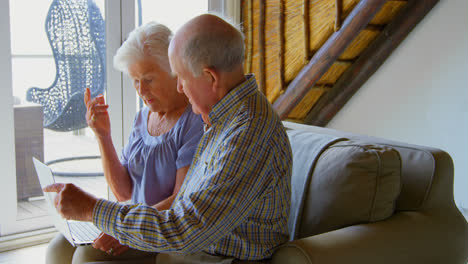 Side-view-of-Caucasian-senior-couple-using-laptop-at-comfortable-home-4k