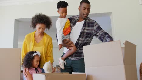 Vorderansicht-Einer-Schwarzen-Familie,-Die-Kartons-In-Einem-Komfortablen-Zuhause-Auspackt,-4K