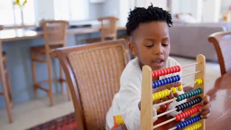 Front-view-of-black-boy-playing-with-abacus-at-comfortable-home-4k