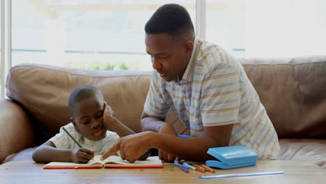 Vorderansicht-Eines-Jungen-Schwarzen-Vaters,-Der-Seinem-Sohn-In-Einem-Komfortablen-Zuhause-Bei-Den-Hausaufgaben-Hilft,-4K