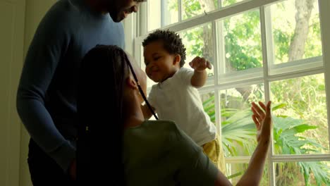 Side-view-of-young-black-parents-playing-with-his-son-on-window-sill-in-a-comfortable-home-4k