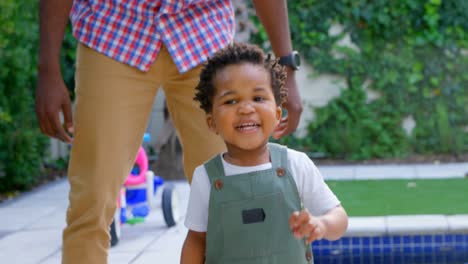 Front-view-of-young-black-father-and-little-son-playing-in-back-yard-of-their-home-4k