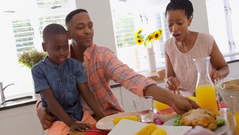 Vista-Frontal-De-Una-Familia-Negra-Feliz-Comiendo-Comida-En-Una-Mesa-De-Comedor-En-Una-Casa-Cómoda-4k