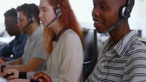 Side-view-of-young-cool-mixed-race-call-center-team-calling-and-sitting-at-desk-of-modern-office-4k