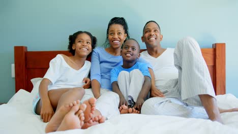 Vorderansicht-Einer-Jungen-Schwarzen-Familie,-Die-Auf-Dem-Bett-Im-Schlafzimmer-Eines-Komfortablen-Zuhauses-Fernsieht,-4K