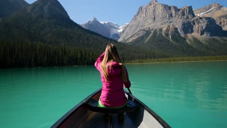 Rear-view-of-young-caucasian-woman-rowing-boat-on-a-turquoise-river-in-the-sunshine-4k
