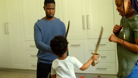 Vorderansicht-Eines-Jungen-Schwarzen-Vaters-Und-Sohnes,-Der-In-Einem-Komfortablen-Zuhause-Mit-Einem-Spielzeugschwert-Spielt,-4K