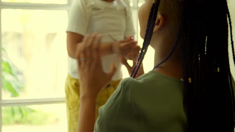 Rear-view-of-young-black-mother-playing-with-his-son-on-window-sill-in-a-comfortable-home-4k