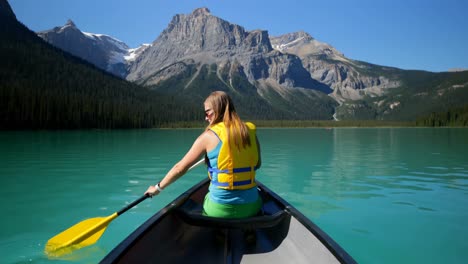 Rear-view-of-young-caucasian-woman-rowing-boat-on-a-turquoise-river-in-the-sunshine-4k
