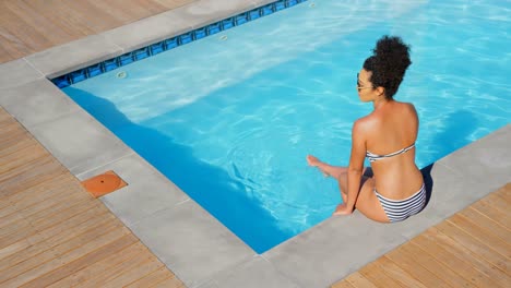 High-angle-view-of-young-mixed-race-woman-relaxing-at-poolside-on-a-sunny-day-4k