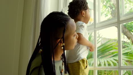 Seitenansicht-Einer-Jungen-Schwarzen-Mutter,-Die-Mit-Ihrem-Sohn-Auf-Der-Fensterbank-In-Einem-Komfortablen-Zuhause-Spielt,-4K